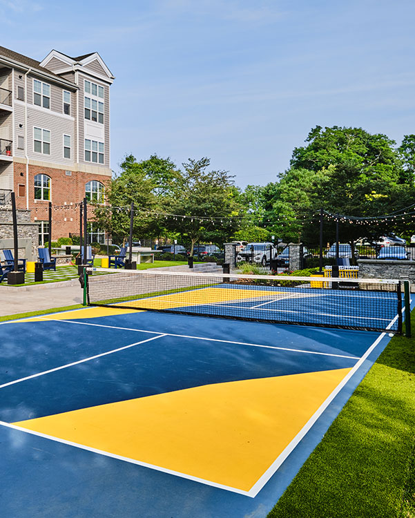 Outdoor pickleball court with vibrant blue and yellow surfaces near residential complex