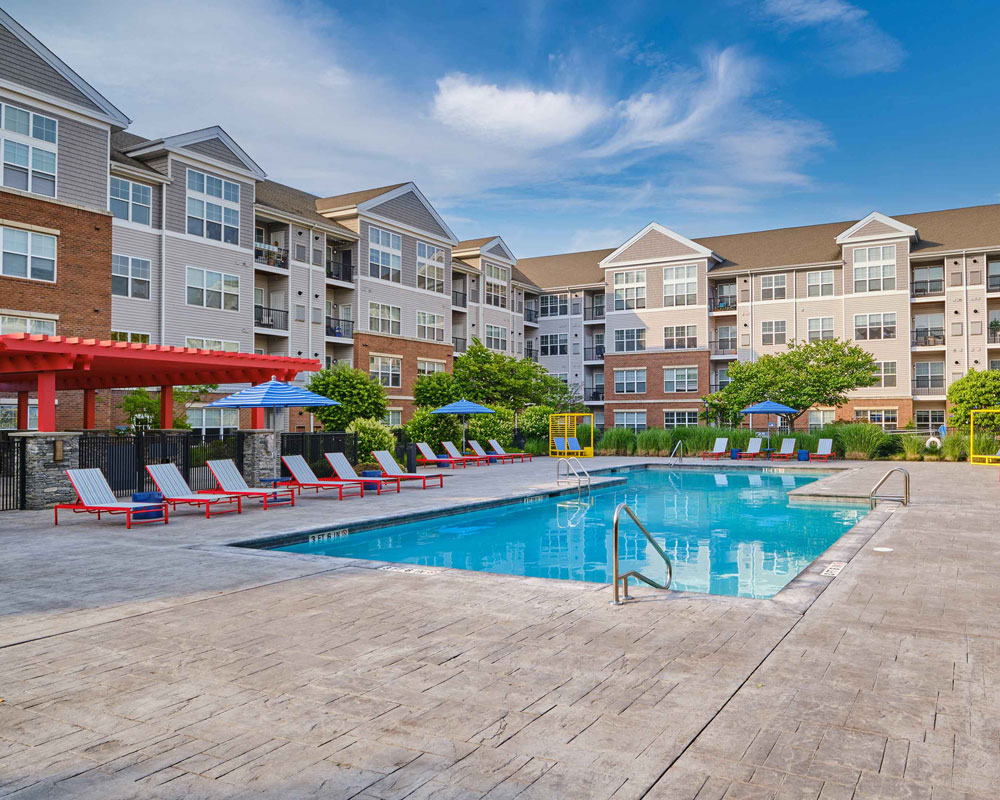 Apartment pool area with red pergola and furniture